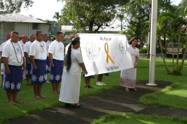 Ladies from the Pago Pago Department of Public Safety, American Samoa, hold up a sign expressing their feelings for the Soldiers of the 100th Battalion, 442nd Infantry to return ho