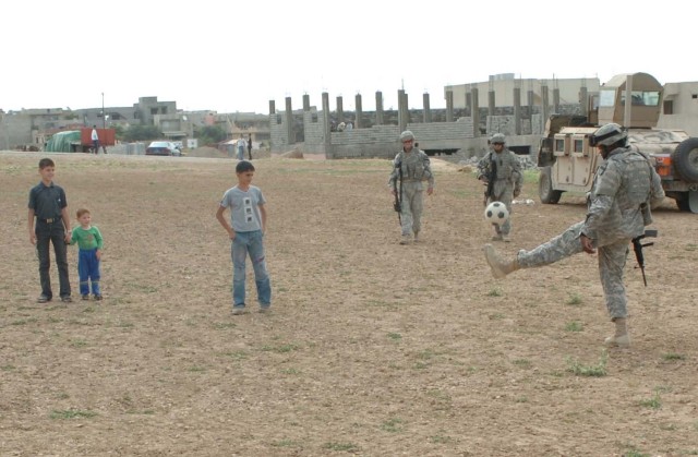 Soldiers with the 27th Brigade Support Battalion take time to play with the children on the soccer field in Al Kosh, Iraq
