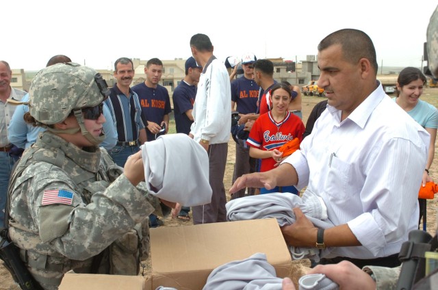 Civil Affairs officer, 1st Lt. Kendra Evers, 27th Brigade Support Battalion, helps hand out new uniforms to the boys and girls softball teams in Al Kosh, Iraq