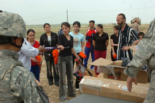 An Al Kosh, Iraq, girl gets handed a new bat by one of the local softball coaches May 19, 2007