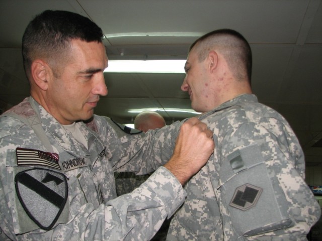 Command Sgt. Maj. Philip Johndrow, the Multi-National Division - Baghdad and 1st Cavalry Division command sergeant major, pins a combat action badge on his nephew, Sgt. Kyle Mostad.  Mostad, a Townsend, Mont. native, earned the CAB during an...