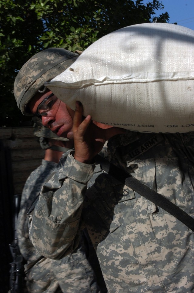 Pfc. Felix Rolan, Battery A, 3rd Battalion, 82nd Field Artillery Regiment, unloads a 50-kilogram (about 110 pound) bag of rice during a humanitarian aid food drop to a home for mentally disabled children in central Baghdad's Qadisiyah neighborhood...