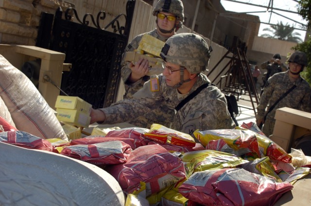 Staff Sgt. Moorehead, from the 422nd Civil Affairs Battalion, and Spc. Justin Reed of Battery A, 3rd Battalion, 82nd Field Artillery Regiment, 2nd Brigade Combat Team, 1st Cavalry Division, unload a trailer full of food being dropped off at a home...
