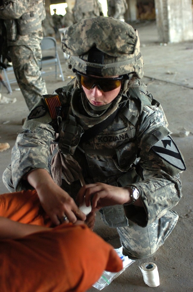 Sgt. Amy Koziana, a Killeen, Texas, native and healthcare specialist with Company C, 15th Brigade Support Battalion, bandages an Iraqi boy's toe during a cooperative medical engagement spearheaded by Company D, 4th Squadron, 9th Cavalry Regiment...