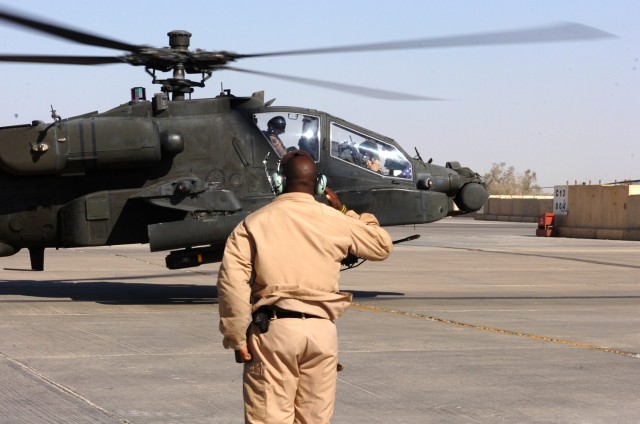 Topeka, Kan., native Spc. Anthony Crawford, an Apache crew chief for Company C, 1st "Attack" Battalion, 227th Aviation Regiment, 1st Air Cavalry Brigade, 1st Cavalry Division, salutes Belton, S.C., native Chief Warrant Officer 3 Russell Motes...