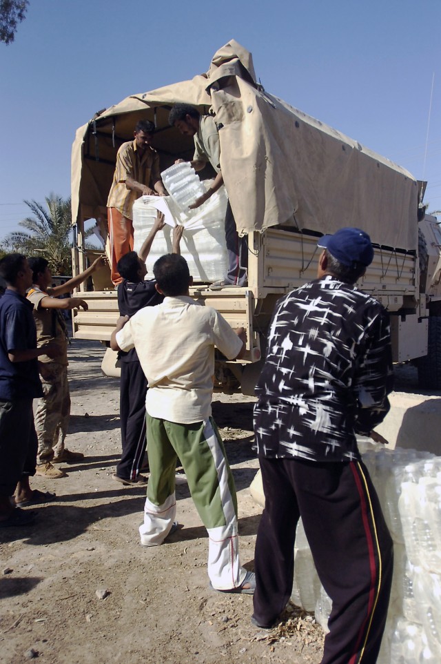 Residents of Bob ab-Durib, a village outside Baqouba, Iraq, unload cases of bottled water in preparation for a humanitarian aid distribution Sept. 27. U.S. Army Soldiers from C. Company, 1-12 Combined Arms Battalion, 3rd Brigade Combat Team, 1st Cava...
