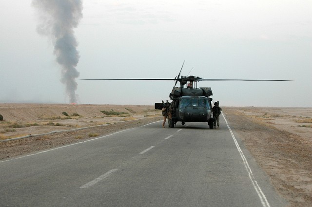 A UH-60 Black Hawk from the 3rd "Spearhead" Battalion, 227th Aviation Regiment, 1st Air Cavalry Brigade, 1st Cavalry Division, lands during an aerial gunnery while the door gunners switch positions, Sept. 30. In the background a target burns after th...