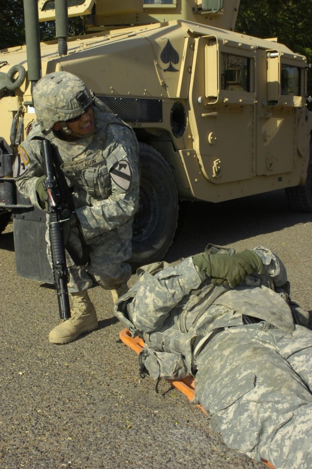 Sgt. Franklin Sagun kneels down beside Spc. Jude Wendel before Wendel is moved into a humvee during a lane training exercise conducted by Soldiers from the 15th Brigade Support Battalion, 2nd Brigade Combat Team, 1st Cavalry Division, in Baghdad\'s I...