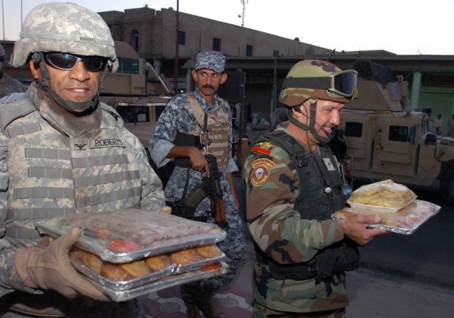 Col. Bryan Roberts, commander of the 2nd Brigade Combat Team, 1st Cavalry Division, and Brig. Gen. Baha, commander of the 5th Brigade, 2nd Iraqi National Police Division, carry food to a mosque in Karkh in honor of the Iftar, or breaking of the fast,...