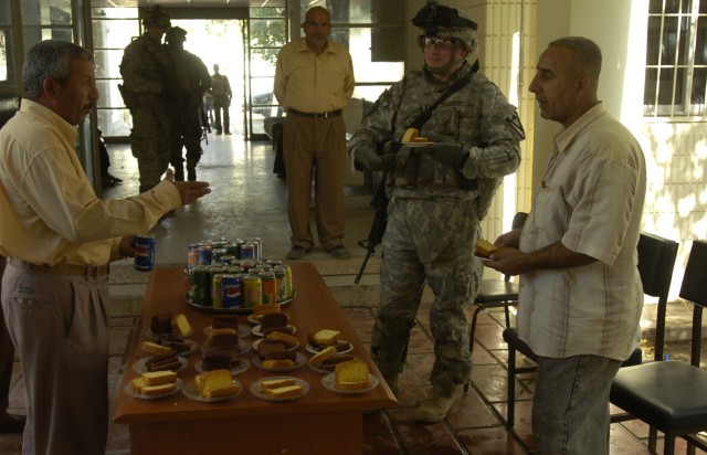 Buffalo, N.Y., native Capt. Joseph Guzowski, the commander of Troop A, 4th Squadron, 9th Cavalry Regiment, 2nd Brigade Combat Team, 1st Cavalry Division, enjoys a piece of cake with staff members of the Omar Muktar Boys' School at a grand opening cer...