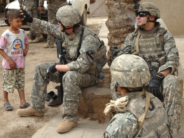 Scouts (left to right) of Troop C, 1st Squadron, 7th Cavalry Regiment, Sgt. Jonathan Toth of Clinton, Miss., Pfc. Zach Foege who hails from Watertown, Wisc. and Pvt. Joseph Solis of Dallas get to know an Iraqi boy during a foot patrol in the...