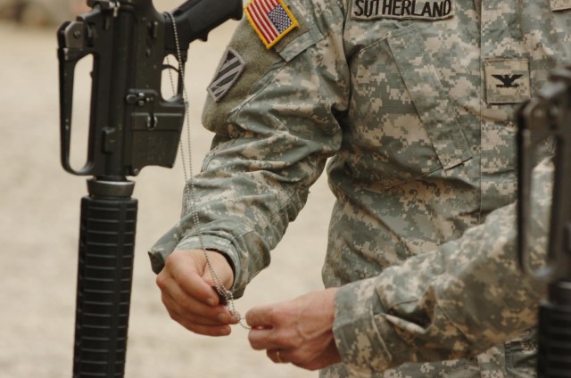 While paying their last respects, Col. David Sutherland, commander for the 3rd Brigade Combat Team, 1st Cavalry Division, and Command Sgt. Maj. Donald Felt, the brigade command sergeant major, hold the ID tags of a fallen Soldier while saying a praye...