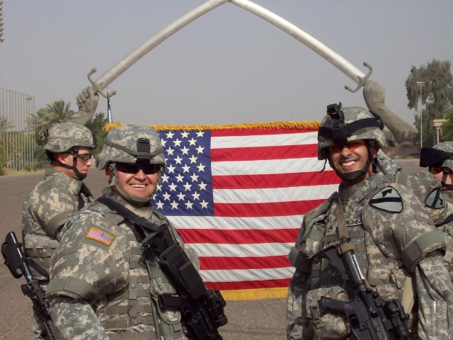 Staff Sgt. Gustavo Sanchez (right), with Forward Support Company D, 4th Squadron, 9th Cavalry Regiment, 2nd Brigade Combat Team, 1st Cavalry Division, pose for a photo after reenlisting in front of the Crossed Sabers in the International Zone on July...