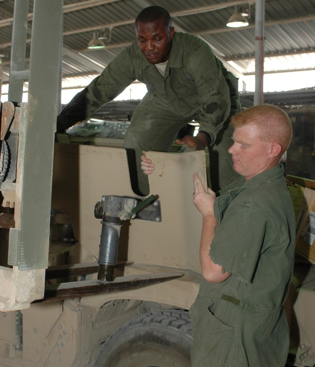 Two Soldiers from 68th Combat Sustainment Support Battalion, 15th Sustainment Brigade, remove part of a gun turret from atop a high mobility multi-wheeled vehicle.  Brigade troops, in both Camp Taji and Baghdad, worked constantly to install improved ...