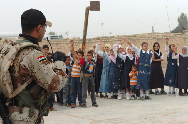 The Iraqi Army "junior hero" (left), an Iraqi Army soldier from the 3rd Battalion, 2nd Brigade, 9th Iraqi Army Division (Mechanized) gives the "allegiance for good" oath to children at an elementary school in Jerf Al-Mila, Iraq Oct. 17 inducting...