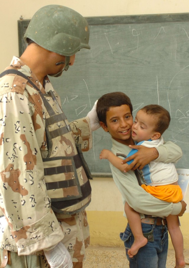 An Iraqi Army medic (left) from the 3rd Brigade, 6th Iraqi Army Division gets to know some young patients during a combined medical effort (CME) in Fira Shia, Iraq Oct. 19. The event was coordinated by medical professionals from the Fires "Hell" Squa...