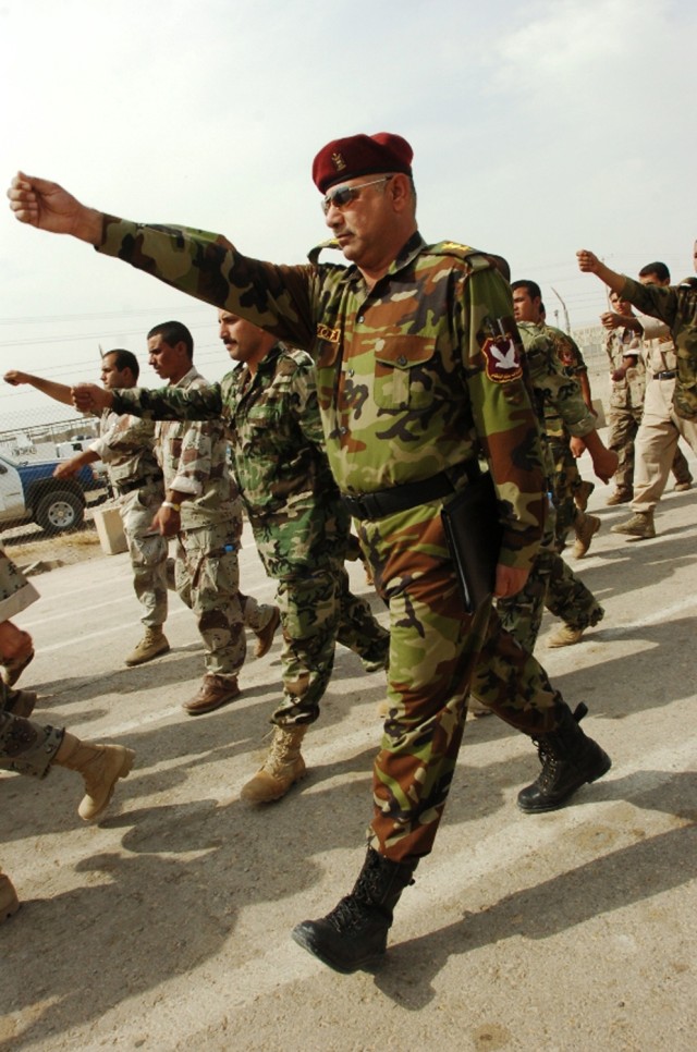 The commander of the 3rd Battalion, 5th Brigade, 2nd Iraqi National Police Division, demonstrates the proper form to his policemen while they march after a training exercise that is part of a month-long stay at the National Police Academy in...