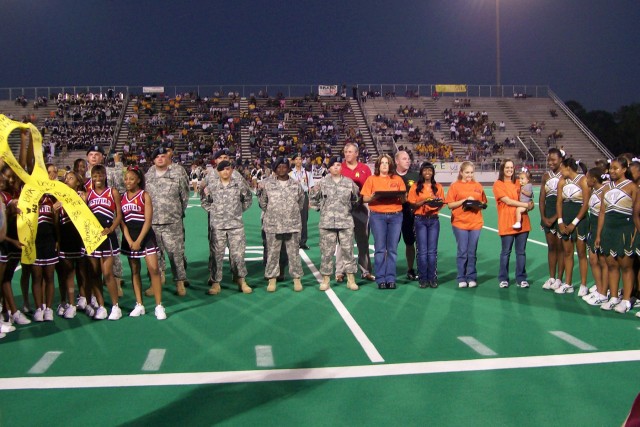 Soldiers and family members stand with the cheerleaders of Klein Forest and Westfield High Schools before they revealed that they were able to raise nearly $4,000 for the 15th Sustainment Brigade's Family Readiness Group in just two weeks of fund rai...