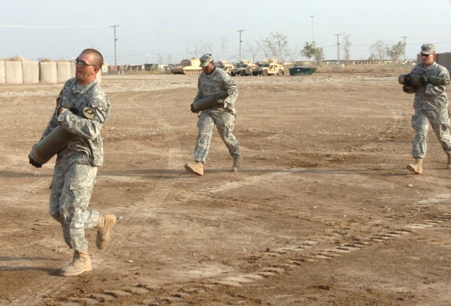 In a team effort, crew members of an M109A6 Paladin howitzer--Soldiers from Battery A, 1st Battalion, 82nd Field Artillery Regiment-- quickly carry 103-pound, 155 millimeter rounds to their Paladin howitzer during the timed red legs relay portion...