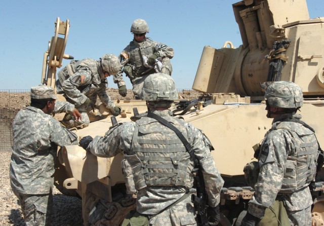 As Colquitt, Ga., native, Sgt. 1st Class Jamie Crankfield (left), battalion master gunner for the 1st Battalion, 82nd Field Artillery Regiment, evaluates them, Soldiers from Battery B perform a maintenance check on their M109A6 Paladin howitzer...