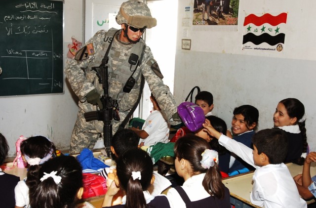 1st Lt. Chris Gallion, a platoon leader with Company E, 1st Battalion, 5th Cavalry Regiment, passes out soccer balls to children at the Harthia Primary School in central Baghdad's Kindi neighborhood Oct. 23. Gallion's unit operates in central Baghdad...