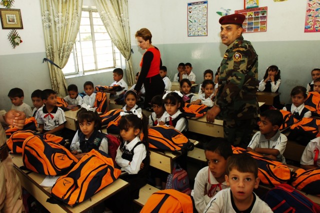 A teacher at Harthia Primary School and an Iraqi Army soldier walk through a classroom after handing out backpacks to the students during a backpack drop Oct. 23 in central Baghdad's Kindi neighborhood. The operation was conducted by troops from Comp...