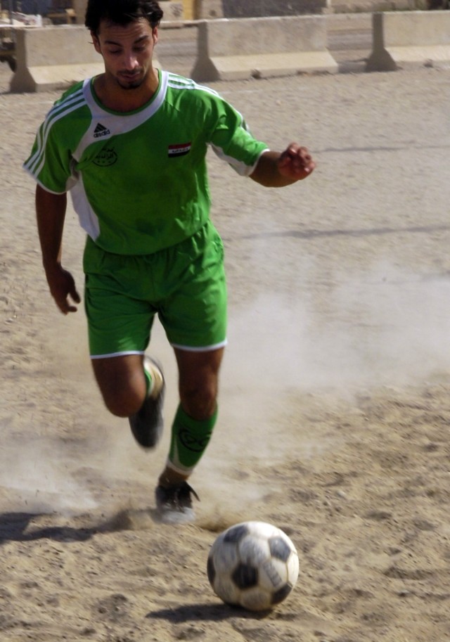 A member of the Forsan Al Rafadeen (FAR) volunteer security organization in Ameriya, a neighborhood in the western Baghdad Al Mansour District, kicks the ball down the field in a soccer game against the 1st Battalion, 5th Cavalry Regiment team...