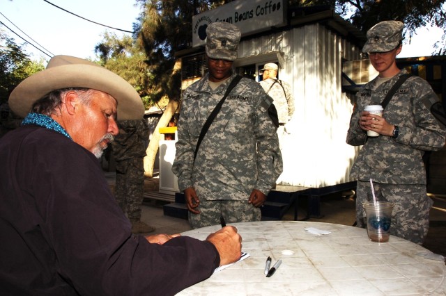 Freddie Fuller, a Saledo, Texas native who goes by the name, "The Singing Cowboy," signs an autograph for Sgt. 1st Class Angela Parker, while Staff Sgt. Ludmila Walsh looks on, after a performance for Soldiers of the 2nd Brigade Combat Team, 1st...