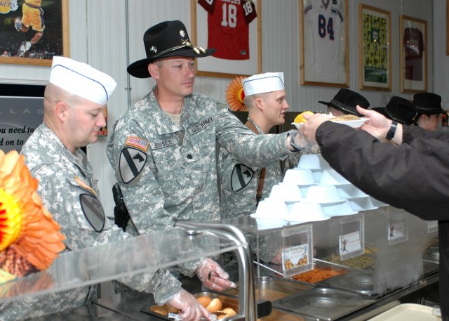 1st Air Cavalry Brigade staff officers, from left to right, Maj. Fred West, Lt. Col. Tom Jessee and Capt. Darin Howe serve the Thanksgiving meal to Soldiers, civilians and contractors at the dining facility Command Sgt. Maj. Cooke Dining Facility Nov...