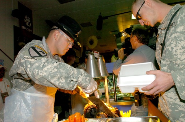 Capt. Lexie R. Gibbs III, commander of Headquarters and Headquarters Company, 2nd "Black Jack" Brigade Combat Team, 1st Cavalry Division, carves a piece of pot roast for a Soldier during the Thanksgiving Day meal at the Black Jack Bistro Dining Facil...