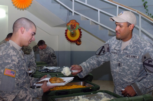 1st Sgt. Uhuru Salmon (right), the top noncommissioned officer of  Troop B, 1st Squadron, 7th Cavalry Regiment, 1st "Ironhorse" Brigade Combat Team, 1st Cavalry Division, serves the traditional American Thanksgiving meal at a joint security station n...