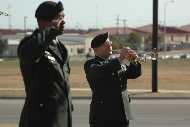 Spc. David A. Rivera, a bugler with the 1st Cavalry Division Band, plays "Taps" while Sgt. Ver Venir Astorga, the firing team noncommissioned officer in charge, renders honors as the 1st Cavalry Division Memorial comes to a close at Fort Hood, Texas ...
