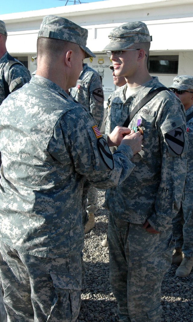 Col. Paul E. Funk II, commander, 1st "Ironhorse" Brigade Combat Team, 1st Cavalry Division attaches the Army Commendation Medal with "V" device to the blouse of Spc. James Byington of Company D, 2nd "Stallion" Battalion, 8th Cavalry Regiment, who hai...