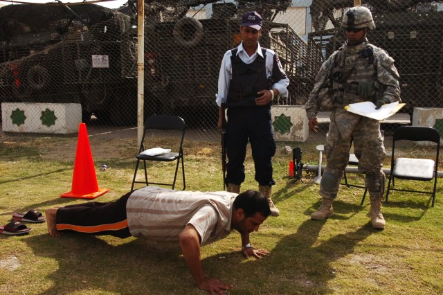 An applicant performs push-ups as part of the physical fitness test given to potential Iraqi police recruits, while a police officer and Staff Sgt. Edmund Savedra, with Headquarters and Headquarters Troop, 4th Squadron, 2nd Stryker Cavalry...