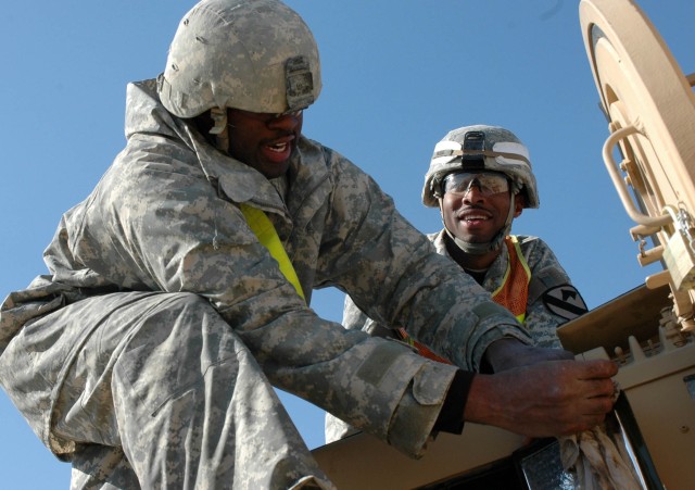 Staff Sgt. Ernest Moore, Company D, 6-9th Armored Reconnaissance Squadron, 3rd Brigade Combat Team, 1st Cavalry Division, supervises Spc. Damon Cobbs, Co. A, 1-12th Combined Arms Battalion, as Cobbs cleans the turret of a Bradley Fighting Vehicle...