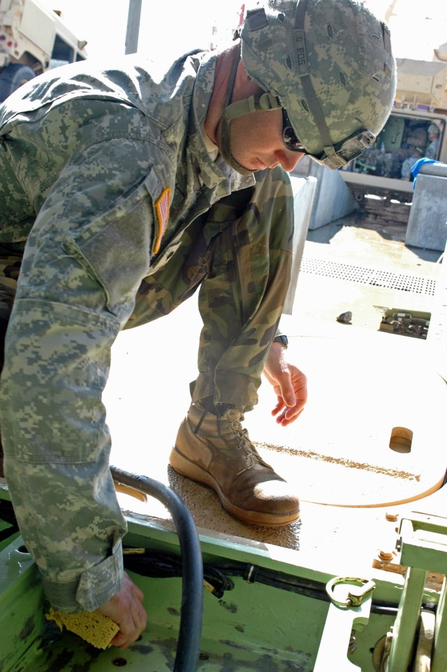 Spc. Adam Barnes, a Soldier with Company B, 3-8th Combined Arms Battalion, 3rd Brigade Combat Team, 1st Cavalry Division, uses a sponge to clean the cracks in the floorboard of a Bradley Fighting Vehicle during the wash rack detail at Kuwait Naval...