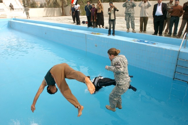Carlisle, Pa., native Capt. Amy Cronin, the special projects officer for the 15th Brigade Support Battalion, 2nd  Brigade Combat Team, 1st Cavalry Division, "christens" the new children's pool with a couple of Iraqi men during its grand opening cerem...