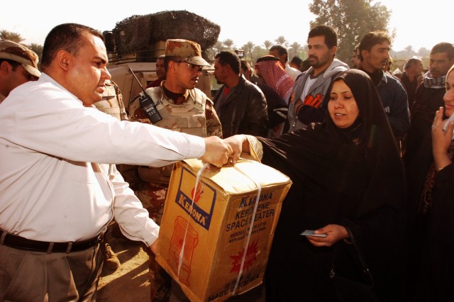 A resident of the Quds Camp in central Baghdad receives a heater from Janeen Neighborhood Advisory Council chairman Udai Ra'ed, during a humanitarian aid mission conducted by Soldiers from 3rd Battalion, 82nd Field Artillery Regiment, 2nd Brigade...