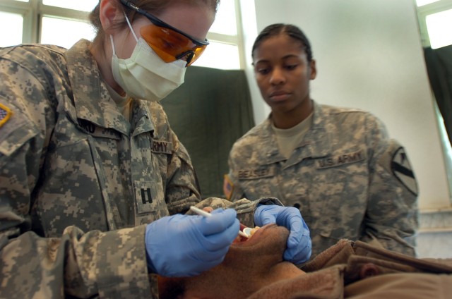 Capt. Christine Ford and East St. Louis, Ill., native Spc. Lisa Beasley, from Company C, 15th Brigade Support Battalion, 2nd Brigade Combat Team, 1st Cavalry Division, clean the teeth of an Iraqi man during a cooperative medical engagement hosted...