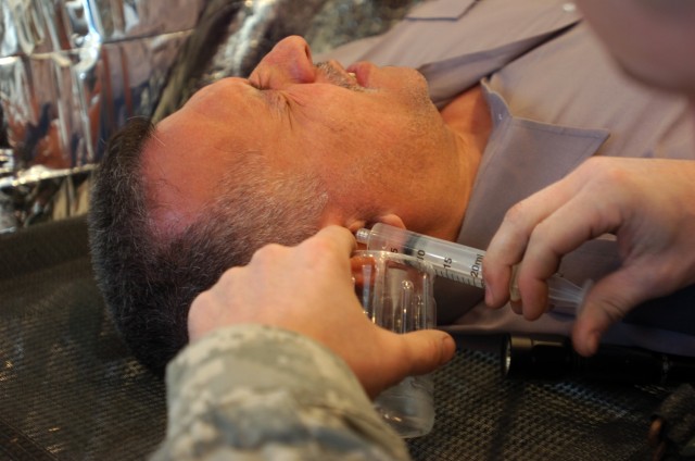 Citrus Heights, Calif., native Spc. Jory Ryland with Company C, 15th Brigade Support Battalion, 2nd Brigade Combat Team, 1st Cavalry Division, irrigates an infected ear canal of a security guard during a cooperative medical engagement hosted by...
