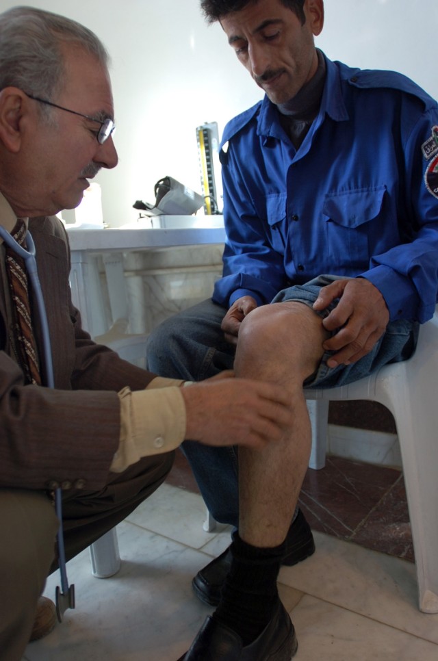 Dr. Asim Izzat, an Iraqi doctor specializing in internal medicine, examines a security guard's leg during a cooperative medical engagement hosted by Soldiers from the 15th Brigade Support Battalion, 2nd Brigade Combat Team, 1st Cavalry Division,...