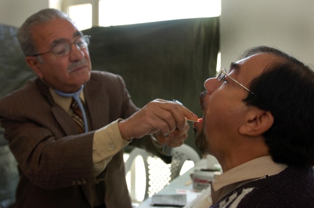 Dr. Asim Izzat, an Iraqi doctor specializing in internal medicine, examines a man during a cooperative medical engagement at the Baghdad Zoo hosted by troops from the 15th Brigade Support Battalion, 2nd Brigade Combat Team, 1st Cavalry Division,...