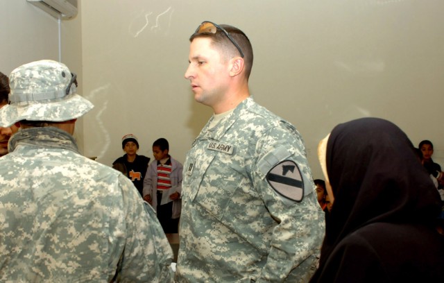 Prior to the start of class, Anchorage, Alaska native Capt. Martin Wohlgemuth (center), commander, Troop D, 1st Battalion, 82nd Field Artillery Regiment, speaks through an interpreter to the instructor of a computer literacy course at the community c...