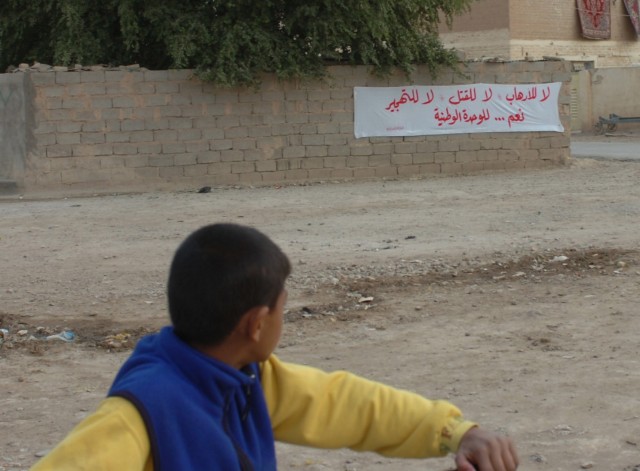 An Iraqi boy riding his bicycle looks toward a sign that reads "no to sectarianism, yes to reconciliation" in the village of Assiriyah, Iraq Dec. 6. While the boy rode his bike, tribal leaders, senior leaders from the Iraqi Security Forces and...