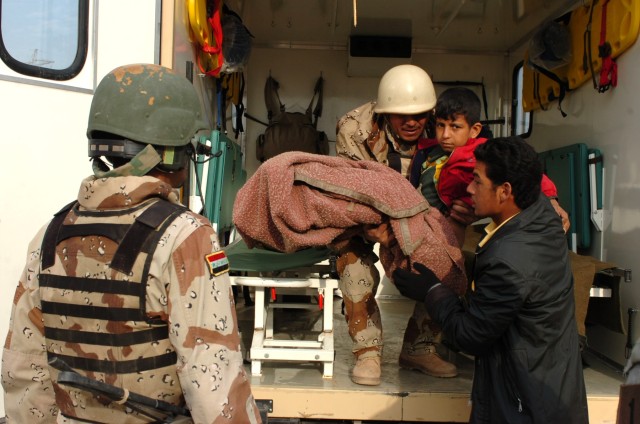 An Iraqi Army medic from the 3rd Brigade, 9th Iraqi Army Division (Mechanized) helps the relative of an Iraqi boy with placing the child into an ambulance in Al Awad, Iraq Dec. 5 as another Iraqi Army soldier (right) stands by to assist. The Iraqi me...