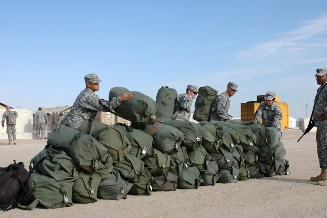 Soldiers from the 1st "Attack" Battalion, 227th Aviation Regiment, 1st Air Cavalry Brigade, 1st Cavalry Division, build a wall of duffle bags as they prepare to move from Camp Virginia, Kuwait, to Ali Al Saleem Air Base and then on to Kuwait City whe...