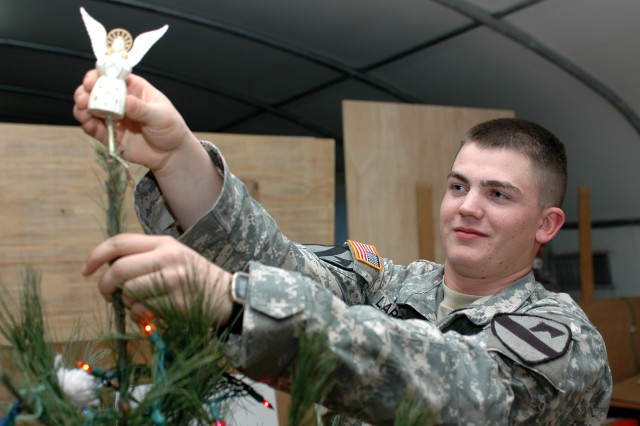 Rangeley, Maine, native Pfc. Rob LaPointe, a fire support specialist for the 1st Air Cavalry "Warrior" Brigade, 1st Cavalry Division, places an angel ornament on top of a real Christmas tree at Camp Virginia, Kuwait, Dec. 12. Like many he works with,...