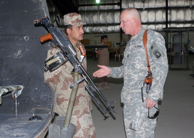 CAMP TAJI, Iraq - Task Force XII Command Sgt. Maj. H. Lee Kennedy tells a member of the Iraqi air force about some of his experiences as a crew chief during an Iraqi Partnership Day Dec. 11.  Members from the Iraqi air force also joined Soldiers...