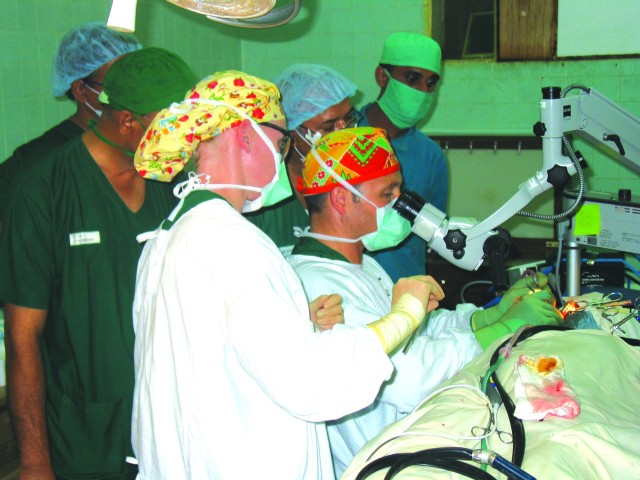 With several Bangladeshi physicians observing, LTC Chris Klem of Tripler Army Medical Center performs ear surgery in Bangladesh, while SPC Andrea Miller assists.