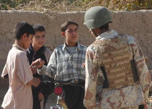 JERF AL MILA, Iraq -- An Iraqi soldier from the 3rd Battalion, 2nd Brigade, 9th Iraqi Army Division (Mechanized) pauses for a moment to speak to some Iraqi boys on the streets of Jerf Al Mila, in northwest Baghdad, Dec. 17 during an event in which...